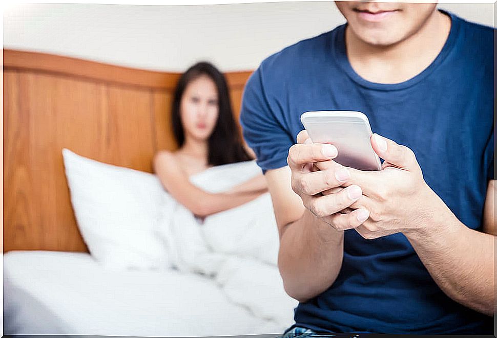 Woman in bed and man watching mobile