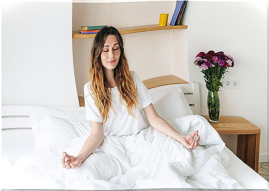 Relaxed woman meditating on her bed.